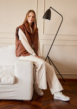 Cargar imagen en el visor de la galería, Chaleco Puffer en color Café. Diseño alcochado en cuero sintético. Tejido técnico repelente al agua. Cuello subido y sin mangas. Bolsillos laterales. Cierre frontal con botones a presión ocultos por la solapa. Forro interior con estampado de Flint. Disponible en color Café y Negro.. Productoo hecho en Colombia. Compra Online