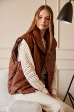 Cargar imagen en el visor de la galería, Chaleco Puffer en color Café. Diseño alcochado en cuero sintético. Tejido técnico repelente al agua. Cuello subido y sin mangas. Bolsillos laterales. Cierre frontal con botones a presión ocultos por la solapa. Forro interior con estampado de Flint. Disponible en color Café y Negro.. Productoo hecho en Colombia. Compra Online