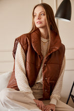 Cargar imagen en el visor de la galería, Chaleco Puffer en color Café. Diseño alcochado en cuero sintético. Tejido técnico repelente al agua. Cuello subido y sin mangas. Bolsillos laterales. Cierre frontal con botones a presión ocultos por la solapa. Forro interior con estampado de Flint. Disponible en color Café y Negro.. Productoo hecho en Colombia. Compra Online