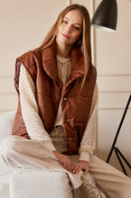 Cargar imagen en el visor de la galería, Chaleco Puffer en color Café. Diseño alcochado en cuero sintético. Tejido técnico repelente al agua. Cuello subido y sin mangas. Bolsillos laterales. Cierre frontal con botones a presión ocultos por la solapa. Forro interior con estampado de Flint. Disponible en color Café y Negro.. Productoo hecho en Colombia. Compra Online