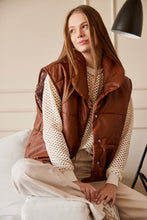 Cargar imagen en el visor de la galería, Chaleco Puffer en color Café. Diseño alcochado en cuero sintético. Tejido técnico repelente al agua. Cuello subido y sin mangas. Bolsillos laterales. Cierre frontal con botones a presión ocultos por la solapa. Forro interior con estampado de Flint. Disponible en color Café y Negro.. Productoo hecho en Colombia. Compra Online