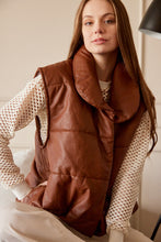 Cargar imagen en el visor de la galería, Chaleco Puffer en color Café. Diseño alcochado en cuero sintético. Tejido técnico repelente al agua. Cuello subido y sin mangas. Bolsillos laterales. Cierre frontal con botones a presión ocultos por la solapa. Forro interior con estampado de Flint. Disponible en color Café y Negro.. Productoo hecho en Colombia. Compra Online