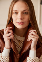 Cargar imagen en el visor de la galería, Chaleco Puffer en color Café. Diseño alcochado en cuero sintético. Tejido técnico repelente al agua. Cuello subido y sin mangas. Bolsillos laterales. Cierre frontal con botones a presión ocultos por la solapa. Forro interior con estampado de Flint. Disponible en color Café y Negro.. Productoo hecho en Colombia. Compra Online