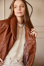 Cargar imagen en el visor de la galería, Chaleco Puffer en color Café. Diseño alcochado en cuero sintético. Tejido técnico repelente al agua. Cuello subido y sin mangas. Bolsillos laterales. Cierre frontal con botones a presión ocultos por la solapa. Forro interior con estampado de Flint. Disponible en color Café y Negro.. Productoo hecho en Colombia. Compra Online