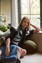 Cargar imagen en el visor de la galería, Chaleco Puffer en color Café. Diseño alcochado en cuero sintético. Tejido técnico repelente al agua. Cuello subido y sin mangas. Bolsillos laterales. Cierre frontal con botones a presión ocultos por la solapa. Forro interior con estampado de Flint. Disponible en color Café y Negro.. Productoo hecho en Colombia. Compra Online