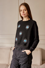 Cargar imagen en el visor de la galería, Saco con ojos de protección bordados. Tejido de algodón. Con detalle de ojos bordados. Diseño recto. Cuello redondo. Manga Larga. Cuello pretina y puños en rib tejido tono a tono. Disponible en color Negro. Porducto hecho en Colombia. Compra Online.