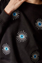 Cargar imagen en el visor de la galería, Saco con ojos de protección bordados. Tejido de algodón. Con detalle de ojos bordados. Diseño recto. Cuello redondo. Manga Larga. Cuello pretina y puños en rib tejido tono a tono. Disponible en color Negro. Porducto hecho en Colombia. Compra Online.