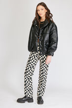 Cargar imagen en el visor de la galería, Chaqueta Puffer de mujer. Diseño alcochado en cuero sintético. Tejido técnico repelente al agua. Cuero Vegano. Cuello subido y manga larga con puños elásticos. Bolsillos laterales. Cierre frontal con botones a presión ocultos por la solapa. Forro interior con estampado de Flint. Disponible en color Café y Negro. Producto 100% hecho en Colombia.