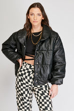Cargar imagen en el visor de la galería, Chaqueta Puffer de mujer. Diseño alcochado en cuero sintético. Tejido técnico repelente al agua. Cuero Vegano. Cuello subido y manga larga con puños elásticos. Bolsillos laterales. Cierre frontal con botones a presión ocultos por la solapa. Forro interior con estampado de Flint. Disponible en color Café y Negro. Producto 100% hecho en Colombia.