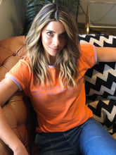 Cargar imagen en el visor de la galería, Camiseta setenteras Flint de mujer cuello redondo. Cool, retro y funky. Disponible en tallas S,M y L. 4 colores azul, rosada, lila y naranja, con rib de colores en cuello y mangas. Frases inspiradas en Paulina de la Mora de la serie Mexicana "La casa de las flores". Fabricada en algodón Peruano. Producto hecho en Colombia. Compra online