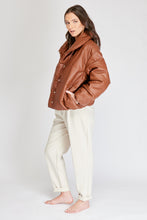 Cargar imagen en el visor de la galería, Chaqueta Puffer de mujer. Diseño alcochado en cuero sintético. Tejido técnico repelente al agua. Cuero Vegano. Cuello subido y manga larga con puños elásticos. Bolsillos laterales. Cierre frontal con botones a presión ocultos por la solapa. Forro interior con estampado de Flint. Disponible en color Café y Negro. Producto 100% hecho en Colombia.