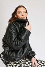 Cargar imagen en el visor de la galería, Chaqueta Puffer de mujer. Diseño alcochado en cuero sintético. Tejido técnico repelente al agua. Cuero Vegano. Cuello subido y manga larga con puños elásticos. Bolsillos laterales. Cierre frontal con botones a presión ocultos por la solapa. Forro interior con estampado de Flint. Disponible en color Café y Negro. Producto 100% hecho en Colombia.