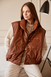 Chaleco Puffer en color Café. Diseño alcochado en cuero sintético. Tejido técnico repelente al agua. Cuello subido y sin mangas. Bolsillos laterales. Cierre frontal con botones a presión ocultos por la solapa. Forro interior con estampado de Flint. Disponible en color Café y Negro.. Productoo hecho en Colombia. Compra Online