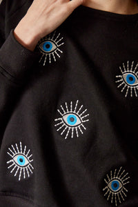 Saco con ojos de protección bordados. Tejido de algodón. Con detalle de ojos bordados. Diseño recto. Cuello redondo. Manga Larga. Cuello pretina y puños en rib tejido tono a tono. Disponible en color Negro. Porducto hecho en Colombia. Compra Online.