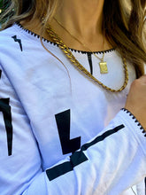Cargar imagen en el visor de la galería, Saco de mujer. Tejido Algodón. Diseño estampado de rayos con bordado de puntadas hechas a mano en terminaciones de cuello y mangas. Diseño recto. Cuello redondo. Manga larga. Disponible en 2 colores, blanco y Negro.  Estas prendas son productos que han sido confeccionadas con fibras y/o procesos de producción sostenible, reduciendo así su impacto ambiental. Producto 100% hecho en Colombia. Compra Online
