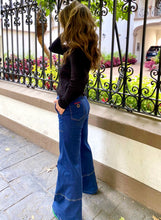 Cargar imagen en el visor de la galería, Jeans setenteros  de mujer Flint, bota campana. Tejido algodón. Modelo bota Campana. Tiro alto. Cuatro bolsillos. Cierre de cremallera y botón. Diseño azul oscuro y Bordado Happy y smiling face en uno de los bolsillos traseros. Producto 100% hecho en Colombia. Compra online
